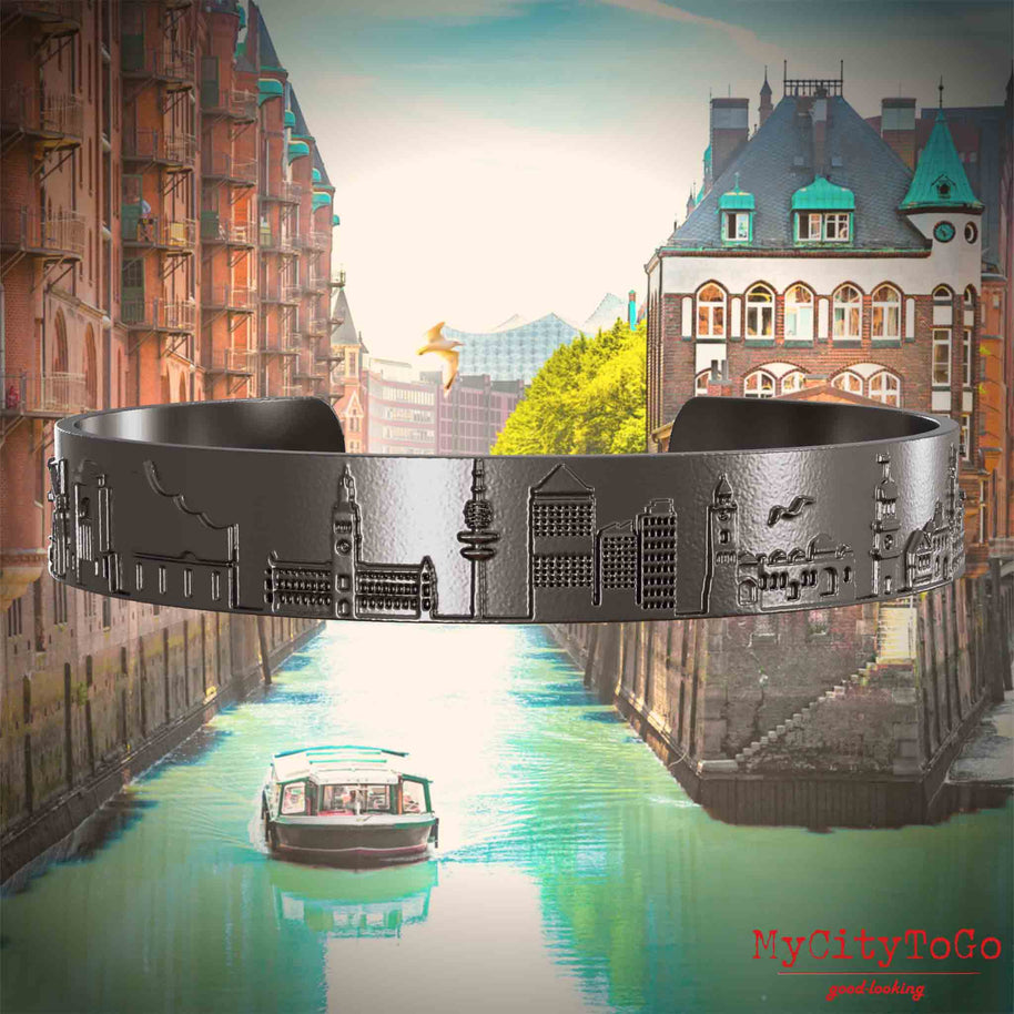 Bangle made of titanium with reliefs of well-known landmarks of the city of Hamburg. The background features a view of the city of Hamburg.
