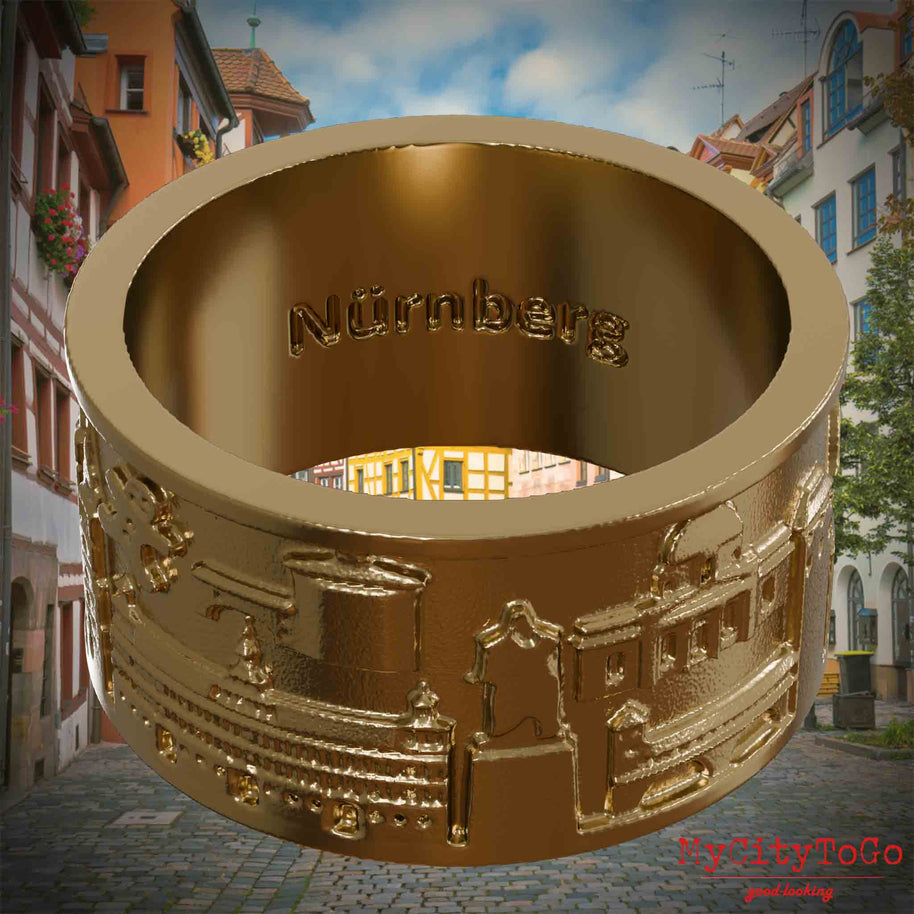 Ring aus vergoldetem Edelstahl mit Reliefs bekannter Sehenswürdigkeiten der Stadt Nuernberg und einer Gravur des Stadtnamens auf der Innenseite. Den Hintergrund bildet eine Ansicht der Stadt  Nuernberg.