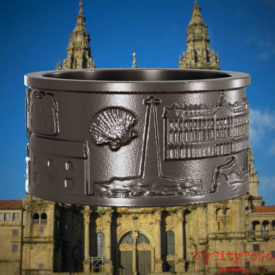 Ring aus Titan mit Reliefs bekannter Sehenswürdigkeiten und Wahrzeichen auf dem Jakobsweg. Den Hintergrund bildet die Kathedrale von Santiago de Compostela.