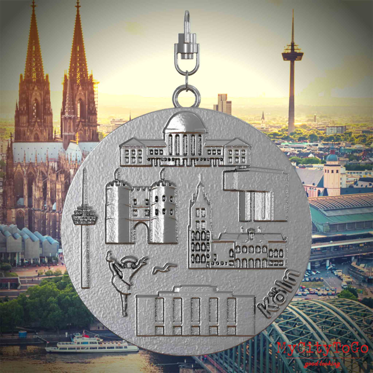 Halskette mit Drehwirbel und Rückseite eines Schmuckanhängers aus Edelstahl, auf dem Reliefs bekannter Sehenswürdigkeiten der Stadt Koeln abgebildet sind. Den Hintergrund bildet eine Ansicht der Stadt Koeln.