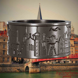 Ring aus Titan mit Reliefs bekannter Sehenswürdigkeiten der Stadt Lyon. Den Hintergrund bildet eine Ansicht der Stadt Lyon.