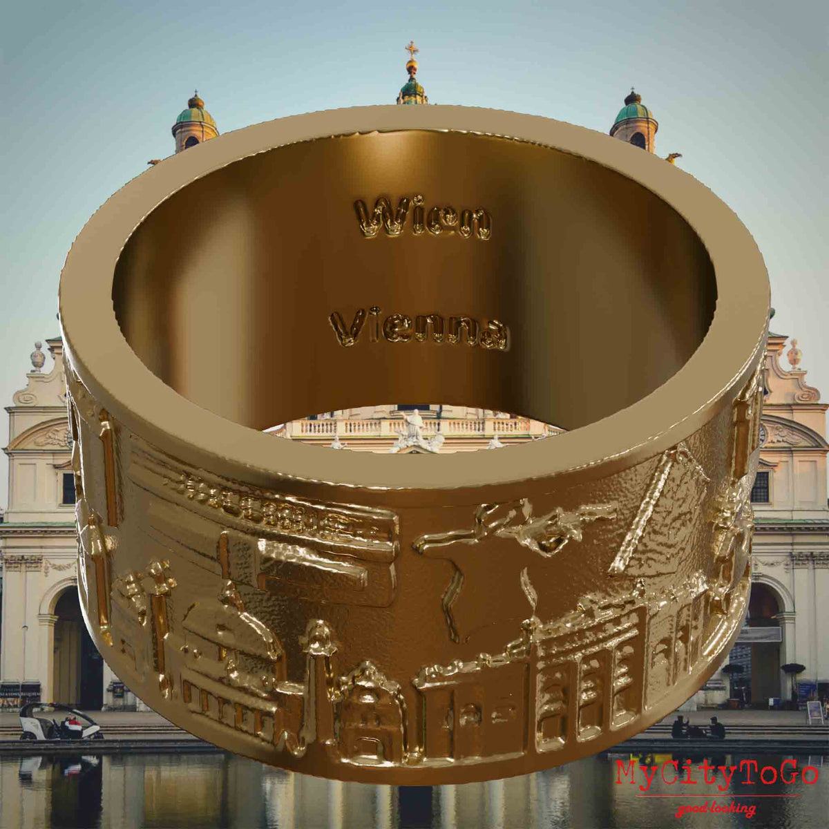Ring aus vergoldetem Edelstahl mit Reliefs bekannter Sehenswürdigkeiten der Stadt Wien und einer Gravur des Stadtnamens auf der Innenseite. Den Hintergrund bildet eine Ansicht der Stadt Wien.