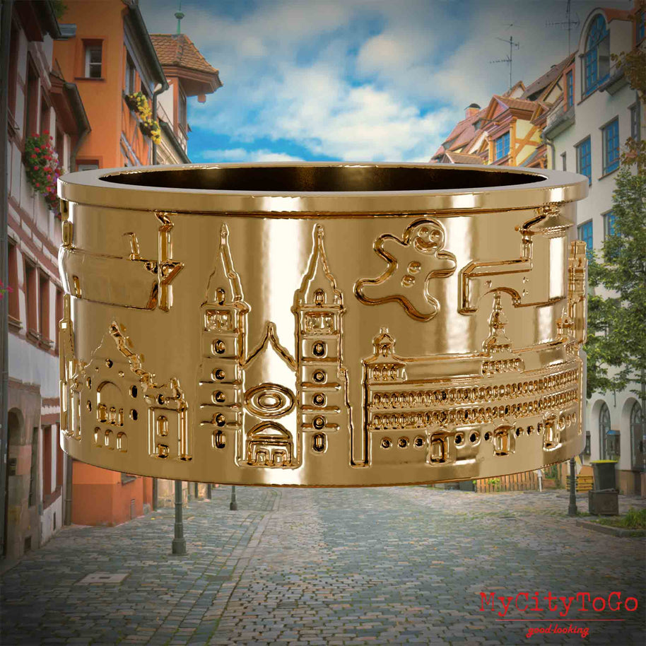 Vergoldeter Ring mit Reliefs bekannter Sehenswürdigkeiten der Stadt Nuernberg. Den Hintergrund bildet eine Ansicht der Stadt  Nuernberg.