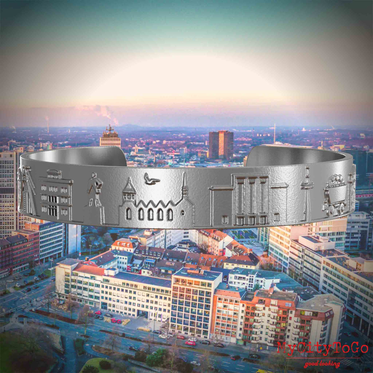 Armreif aus Edelstahl mit Reliefs bekannter Sehenswürdigkeiten der Stadt Essen. Den Hintergrund bildet eine Ansicht der Stadt Essen.