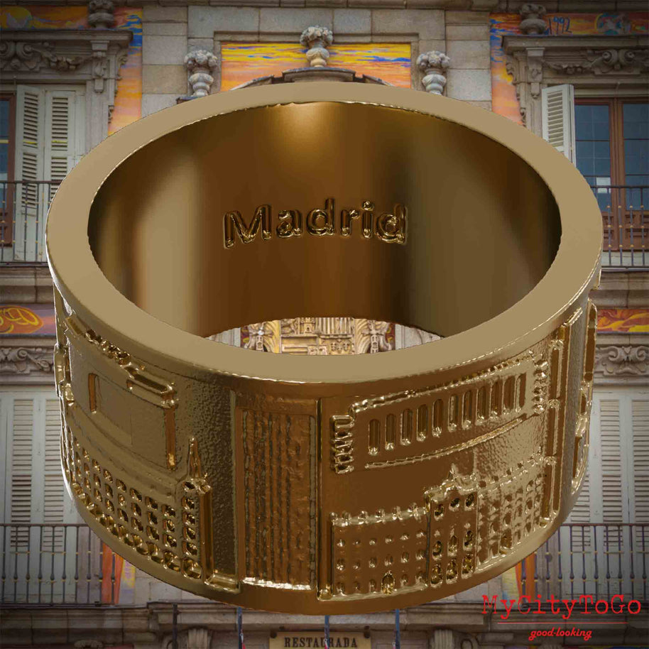 Ring aus vergoldetem Edelstahl mit Reliefs bekannter Sehenswürdigkeiten der Stadt Madrid und einer Gravur des Stadtnamens auf der Innenseite. Den Hintergrund bildet eine Ansicht der Stadt Madrid.
