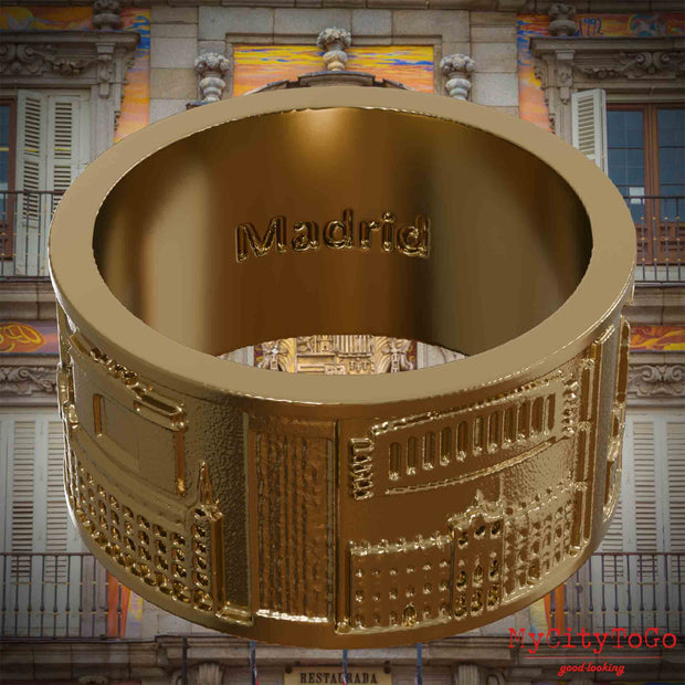 Ring aus vergoldetem Edelstahl mit Reliefs bekannter Sehenswürdigkeiten der Stadt Madrid und einer Gravur des Stadtnamens auf der Innenseite. Den Hintergrund bildet eine Ansicht der Stadt Madrid.