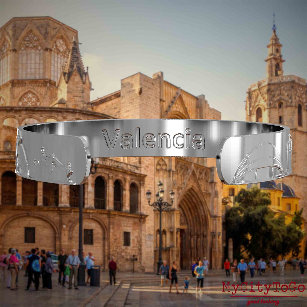 Innenseite eines silbernen Armreifs mit Reliefs bekannter Sehenswürdigkeiten der Stadt Valencia und einer Gravur des Stadtnamens. Den Hintergrund bildet eine Ansicht der Stadt Valencia.