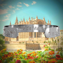 Innenseite eines silbernen Armreifs mit Reliefs bekannter Sehenswürdigkeiten der Stadt Palma de Mallorca und einer Gravur des Stadtnamens . Den Hintergrund bildet eine Ansicht der Stadt Palma de Mallorca.