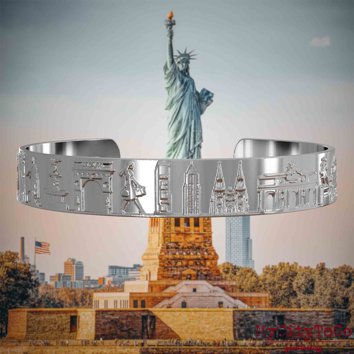 Versilberter Armreif mit Reliefs bekannter Sehenswürdigkeiten der Stadt New York. Den Hintergrund bildet eine Ansicht der Stadt New York.