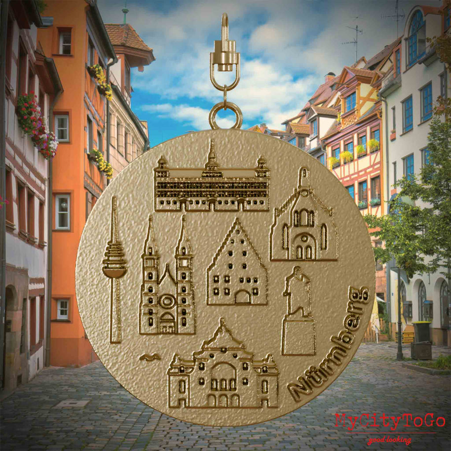 Halskette mit Drehwirbel und Vorderseite eines Schmuckanhängers aus vergoldetem Edelstahl, auf dem Reliefs bekannter Sehenswürdigkeiten der Stadt Nuernberg abgebildet sind. Den Hintergrund bildet eine Ansicht der Stadt Nuernberg.