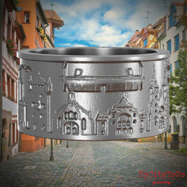 Ring aus Edelstahl mit Reliefs bekannter Sehenswürdigkeiten der Stadt Nuernberg. Den Hintergrund bildet eine Ansicht der Stadt  Nuernberg.