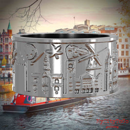 Silberner Ring mit Reliefs bekannter Sehenswürdigkeiten der Stadt Amsterdam. Den Hintergrund bildet eine Ansicht der Stadt Amsterdam.
