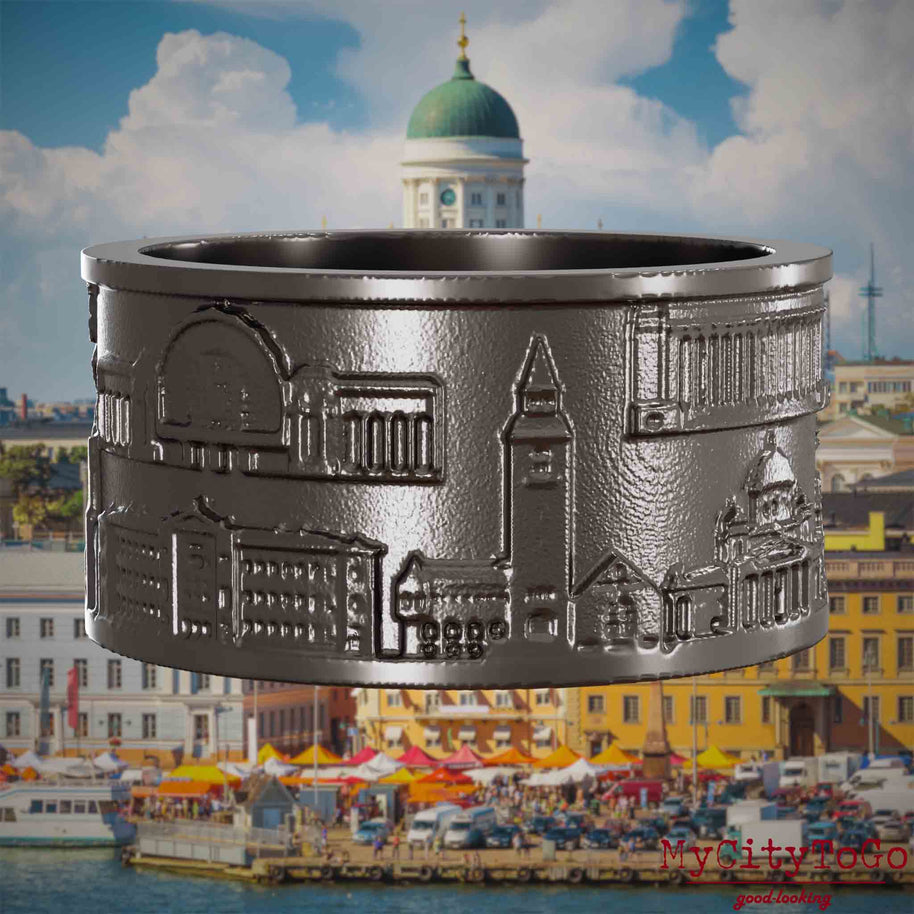Ring aus Titan mit Reliefs bekannter Sehenswürdigkeiten der Stadt Helsinki. Den Hintergrund bildet eine Ansicht der Stadt Helsinki.