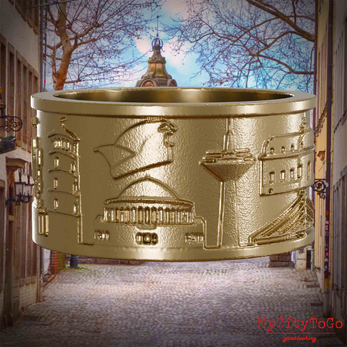 Ring aus vergoldetem Edelstahl mit Reliefs bekannter Sehenswürdigkeiten der Stadt Duesseldorf. Den Hintergrund bildet eine Ansicht der Stadt Duesseldorf.