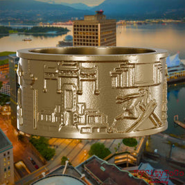 Ring aus vergoldetem Edelstahl mit Reliefs bekannter Sehenswürdigkeiten der Stadt Vancouver. Den Hintergrund bildet eine Ansicht der Stadt Vancouver.