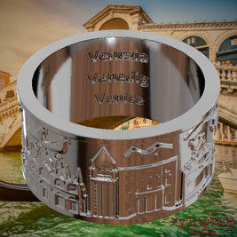 Versilberter Ring mit Reliefs bekannter Sehenswürdigkeiten der Stadt Venedig und einer Gravur des Stadtnamens auf der Innenseite. Den Hintergrund bildet eine Ansicht der Stadt Venedig.