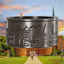 Ring aus Titan mit Reliefs bekannter Sehenswürdigkeiten der Stadt Luebeck. Den Hintergrund bildet eine Ansicht der Stadt Luebeck.