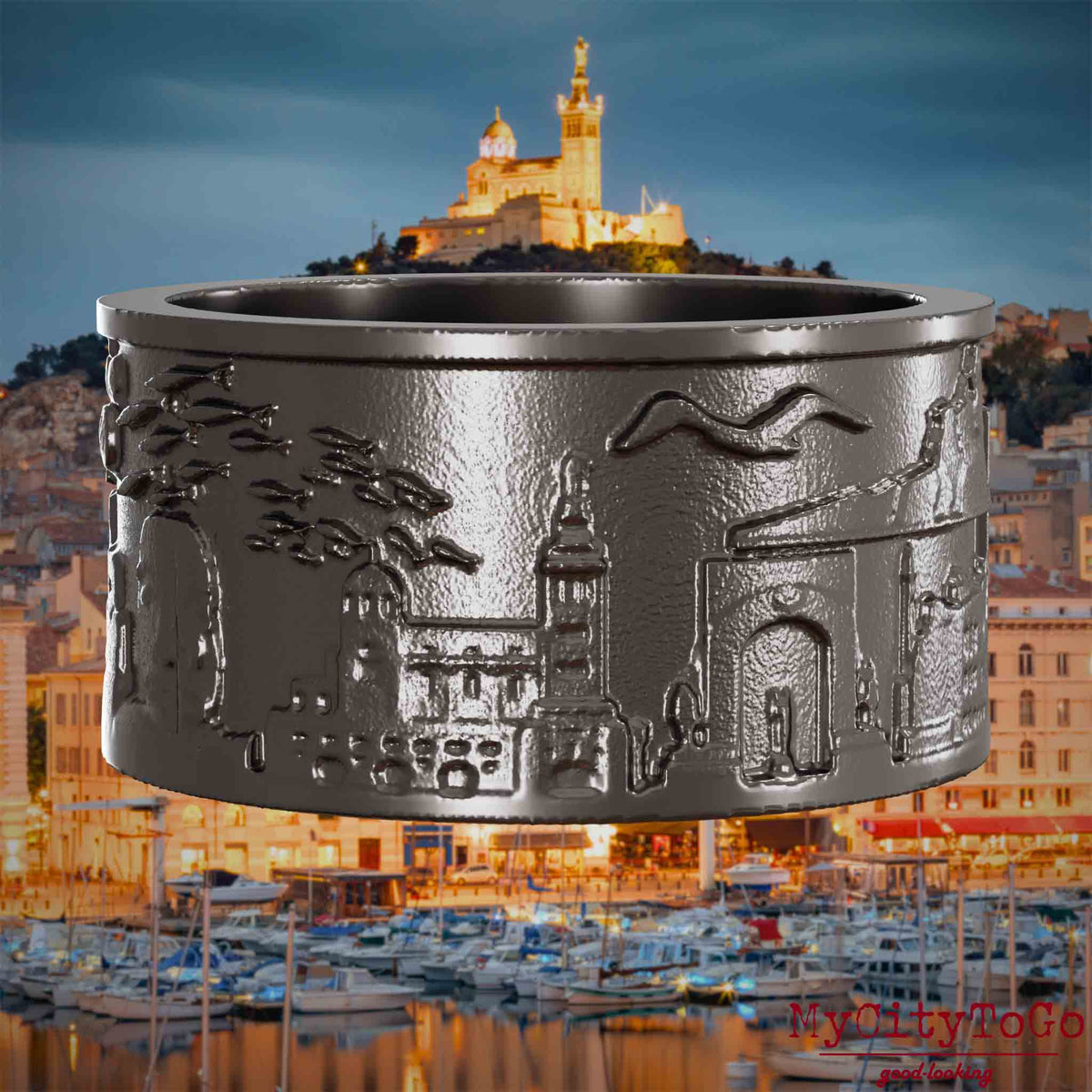 Ring aus Titan mit Reliefs bekannter Sehenswürdigkeiten der Stadt Marseille. Den Hintergrund bildet eine Ansicht der Stadt Marseille.