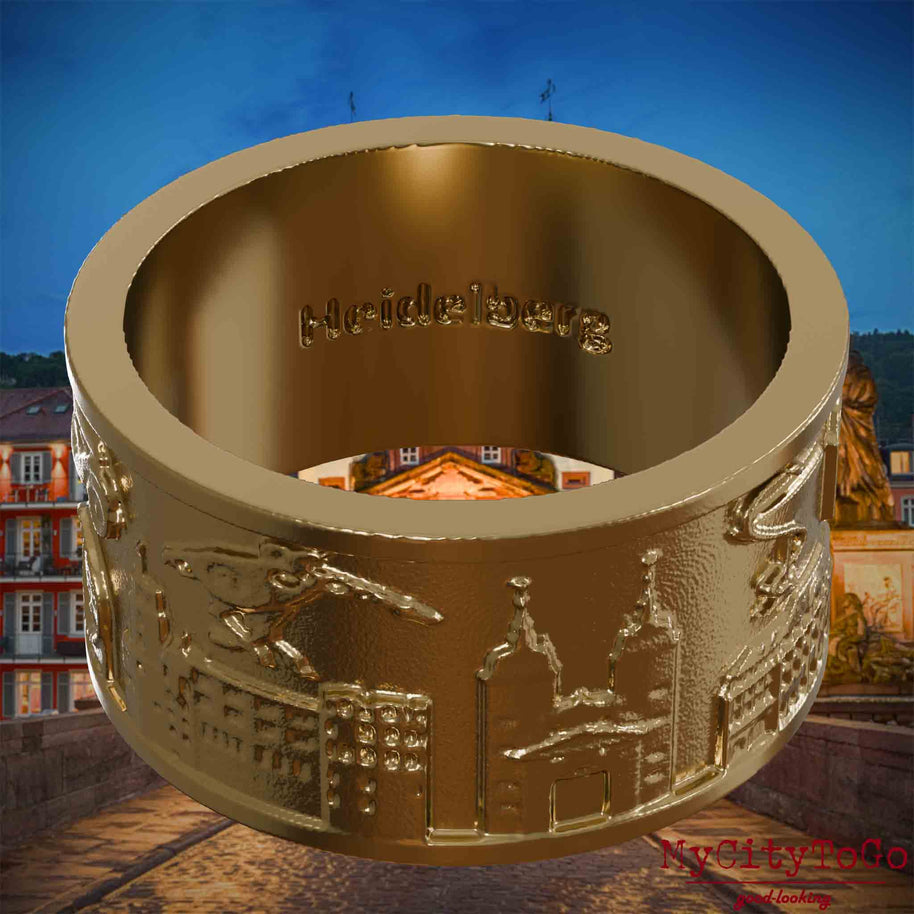 Ring aus vergoldetem Edelstahl mit Reliefs bekannter Sehenswürdigkeiten der Stadt Heidelberg und einer Gravur des Stadtnamens auf der Innenseite. Den Hintergrund bildet eine Ansicht der Stadt Heidelberg.
