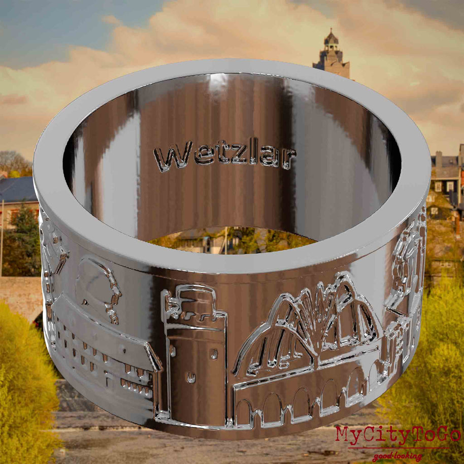 Versilberter Ring mit Reliefs bekannter Sehenswürdigkeiten der Stadt Wetzlar und einer Gravur des Stadtnamens auf der Innenseite. Den Hintergrund bildet eine Ansicht der Stadt Wetzlar.