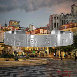 Silberner Armreif mit Reliefs bekannter Sehenswürdigkeiten der Stadt Lissabon. Den Hintergrund bildet eine Ansicht der Stadt Lissabon.