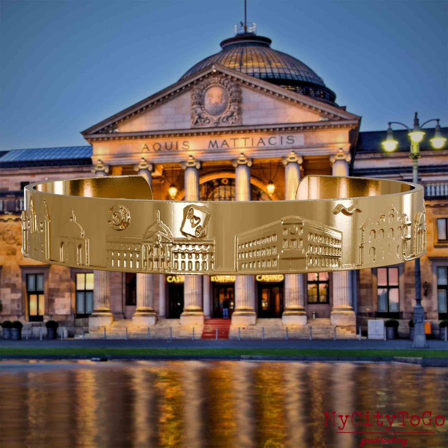 Gold-plated Bangle with reliefs of well-known landmarks of the city of Wiesbaden. The background features a view of the city of Wiesbaden.