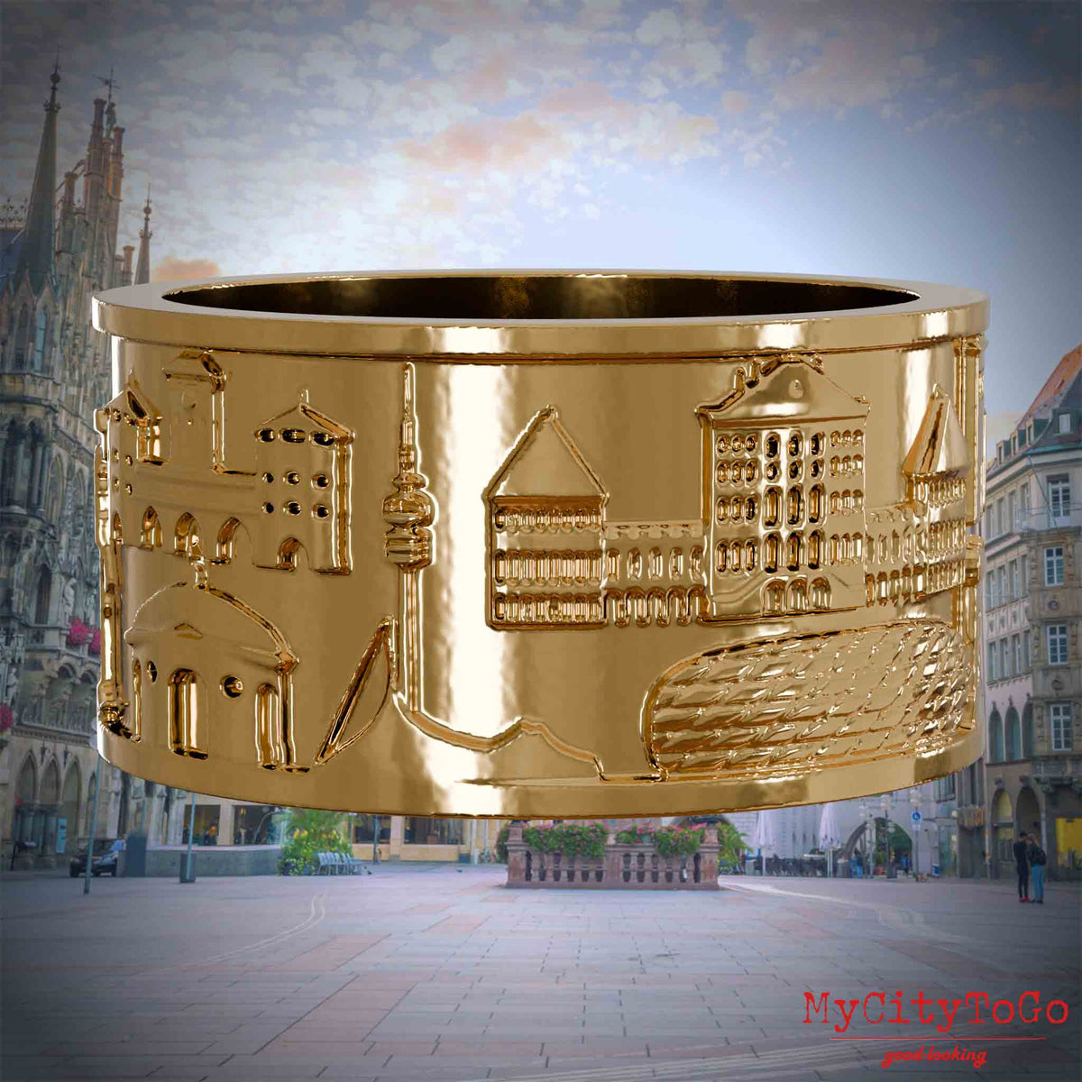 Vergoldeter Ring mit Reliefs bekannter Sehenswürdigkeiten der Stadt Muenchen. Den Hintergrund bildet eine Ansicht der Stadt Muenchen.