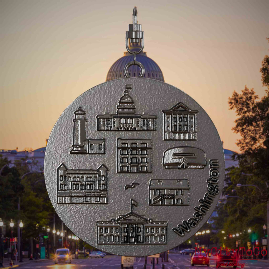 Halskette mit Drehwirbel und Rückseite eines Schmuckanhängers aus Titan, auf dem Reliefs bekannter Sehenswürdigkeiten der Stadt Washington abgebildet sind. Den Hintergrund bildet eine Ansicht der Stadt Washington.
