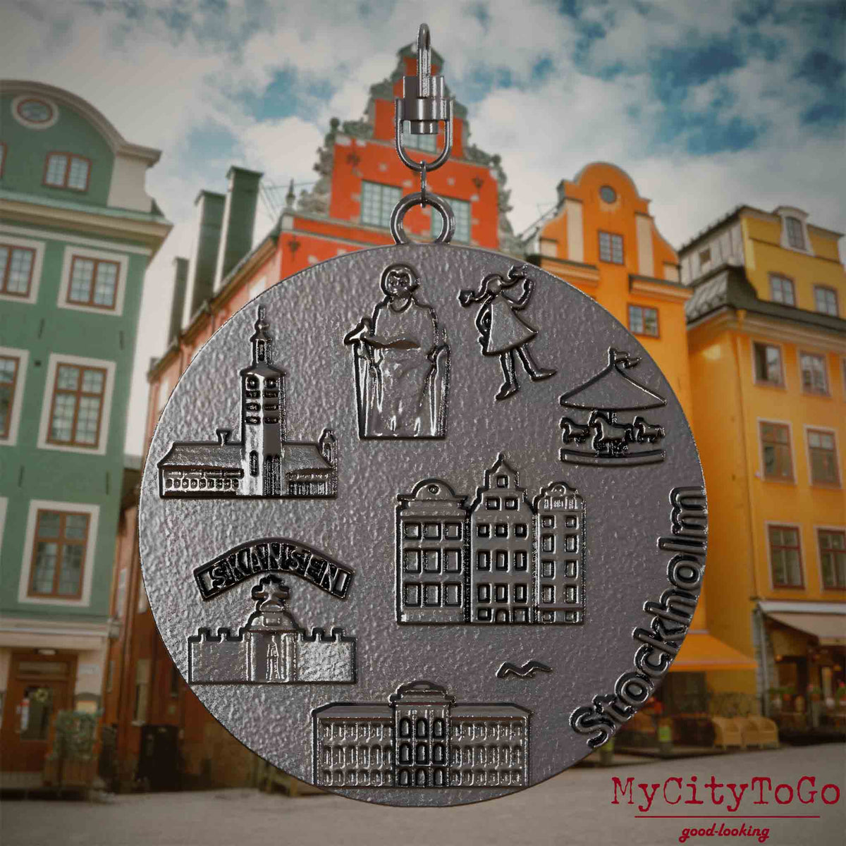 Halskette mit Drehwirbel und Rückseite eines Schmuckanhängers aus Titan, auf dem Reliefs bekannter Sehenswürdigkeiten der Stadt Stockholm abgebildet sind. Den Hintergrund bildet eine Ansicht der Stadt Stockholm.
