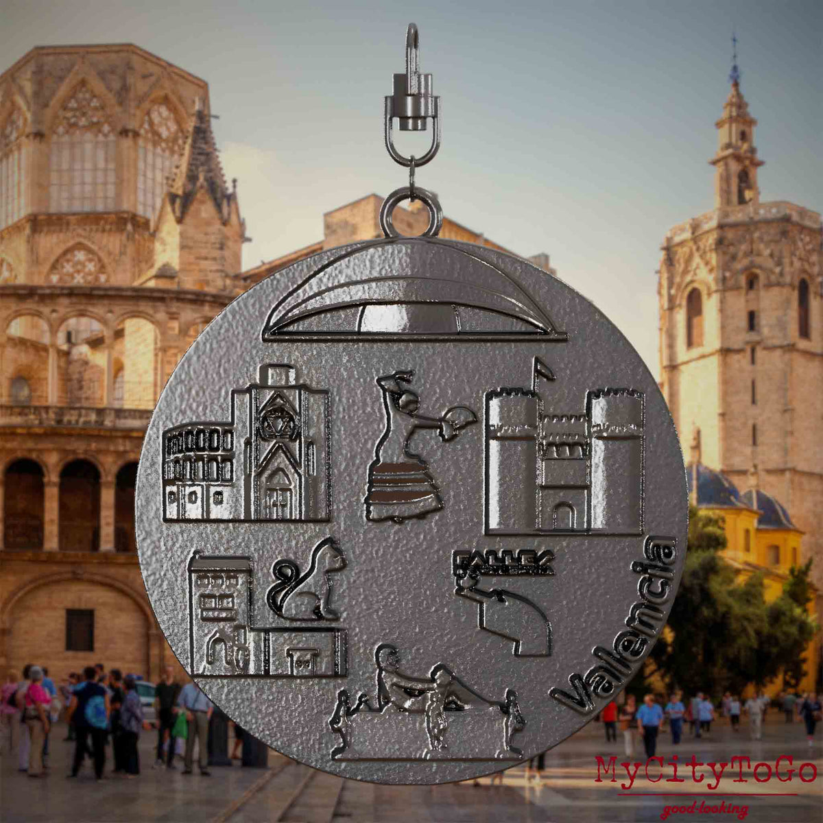 Halskette mit Drehwirbel und Rückseite eines Schmuckanhängers aus Titan, auf dem Reliefs bekannter Sehenswürdigkeiten der Stadt Valencia abgebildet sind. Den Hintergrund bildet eine Ansicht der Stadt Valencia.
