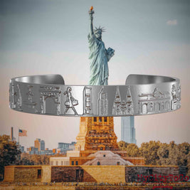 Armreif aus Edelstahl mit Reliefs bekannter Sehenswürdigkeiten der Stadt New York. Den Hintergrund bildet eine Ansicht der Stadt New York.