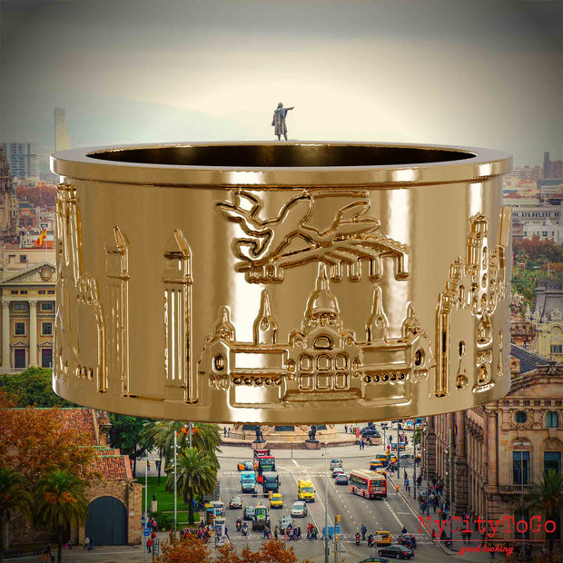 Vergoldeter Ring mit Reliefs bekannter Sehenswürdigkeiten der Stadt Barcelona. Den Hintergrund bildet eine Ansicht der Stadt Barcelona.