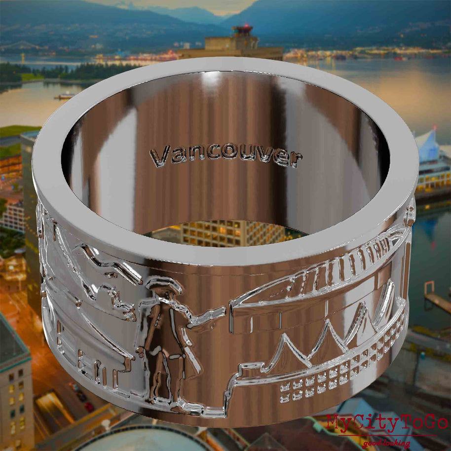 Versilberter Ring mit Reliefs bekannter Sehenswürdigkeiten der Stadt Vancouver und einer Gravur des Stadtnamens auf der Innenseite. Den Hintergrund bildet eine Ansicht der Stadt Vancouver.