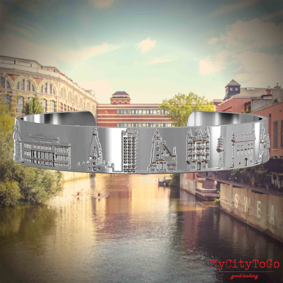 Versilberter Armreif mit Reliefs bekannter Sehenswürdigkeiten der Stad Leipzig. Den Hintergrund bildet eine Ansicht der Stadt Leipzig.