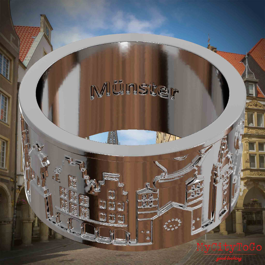 Versilberter Ring mit Reliefs bekannter Sehenswürdigkeiten der Stadt Muenster und einer Gravur des Stadtnamens auf der Innenseite. Den Hintergrund bildet eine Ansicht der Stadt Muenster.
