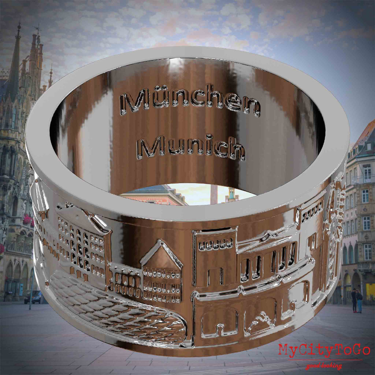 Versilberter Ring mit Reliefs bekannter Sehenswürdigkeiten der Stadt Muenchen und einer Gravur des Stadtnamens auf der Innenseite. Den Hintergrund bildet eine Ansicht der Stadt Muenchen.