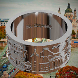 Versilberter Ring mit Reliefs bekannter Sehenswürdigkeiten der Stadt Budapest und einer Gravur des Stadtnamens auf der Innenseite. Den Hintergrund bildet eine Ansicht der Stadt Budapest.