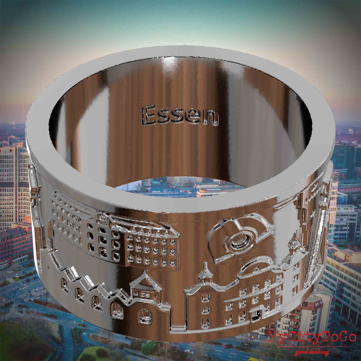 Versilberter Ring mit Reliefs bekannter Sehenswürdigkeiten der Stadt Essen und einer Gravur des Stadtnamens auf der Innenseite. Den Hintergrund bildet eine Ansicht der Stadt Essen.