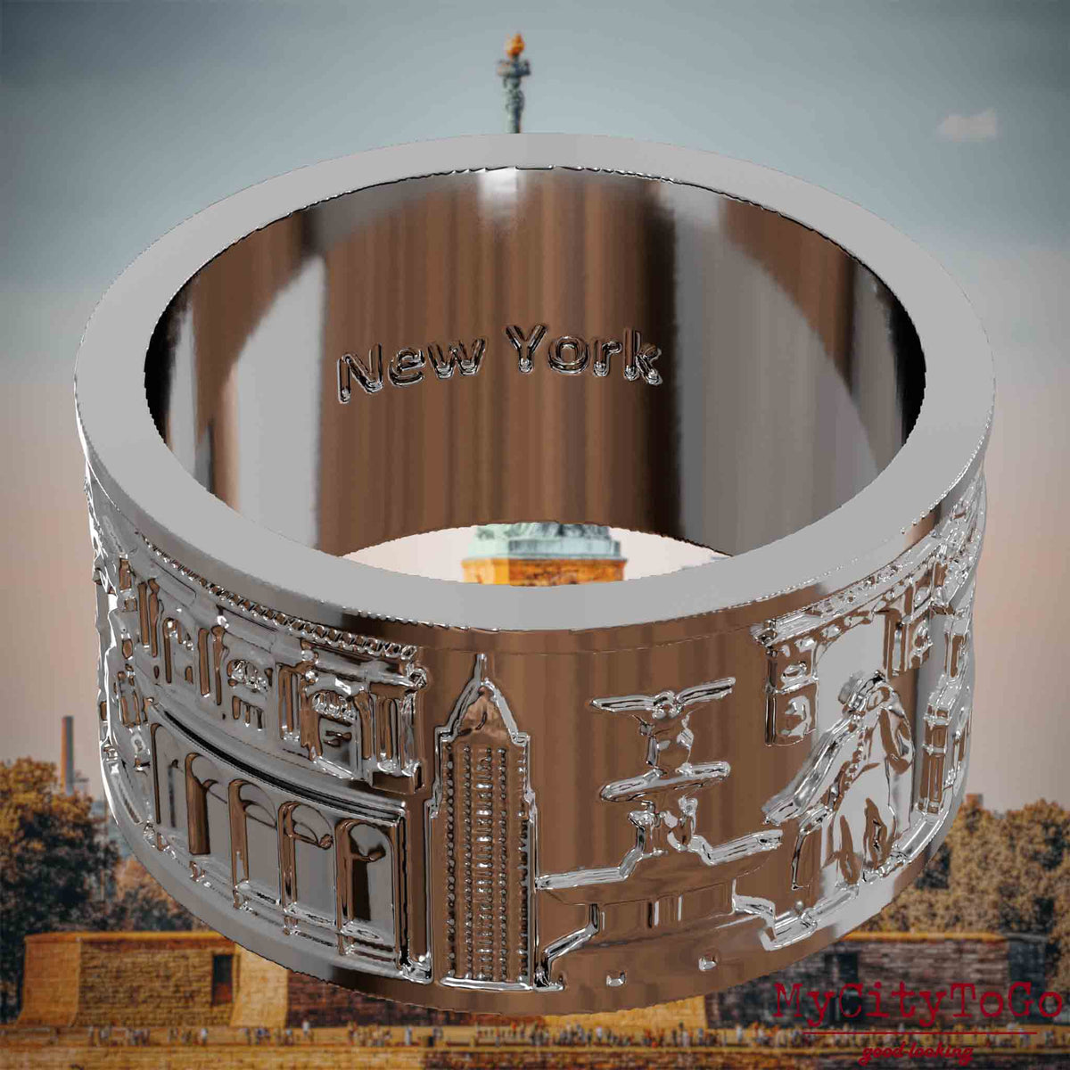 Versilberter Ring mit Reliefs bekannter Sehenswürdigkeiten der Stadt New York und einer Gravur des Stadtnamens auf der Innenseite. Den Hintergrund bildet eine Ansicht der Stadt New York.