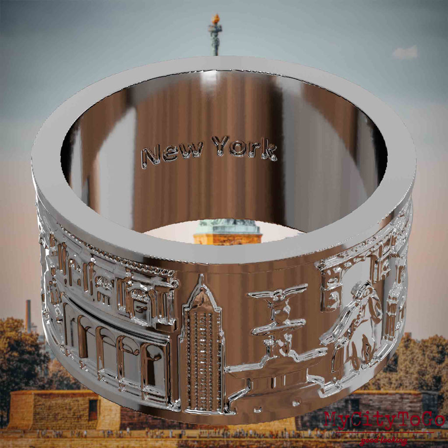 Versilberter Ring mit Reliefs bekannter Sehenswürdigkeiten der Stadt New York und einer Gravur des Stadtnamens auf der Innenseite. Den Hintergrund bildet eine Ansicht der Stadt New York.