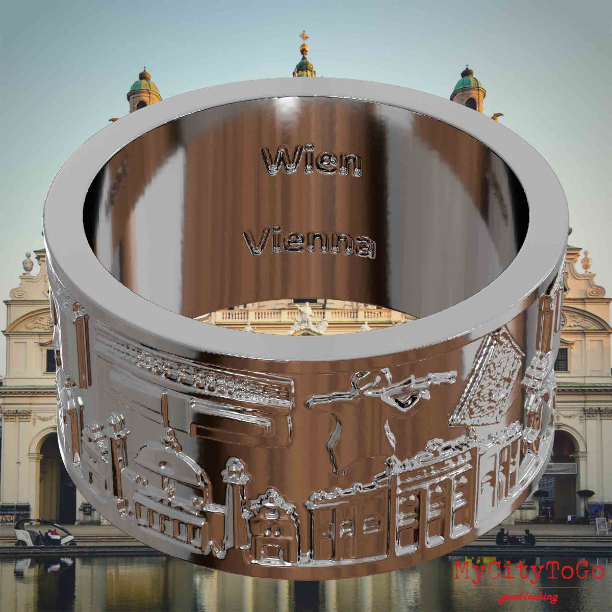 Versilberter Ring mit Reliefs bekannter Sehenswürdigkeiten der Stadt Wien und einer Gravur des Stadtnamens auf der Innenseite. Den Hintergrund bildet eine Ansicht der Stadt Wien.