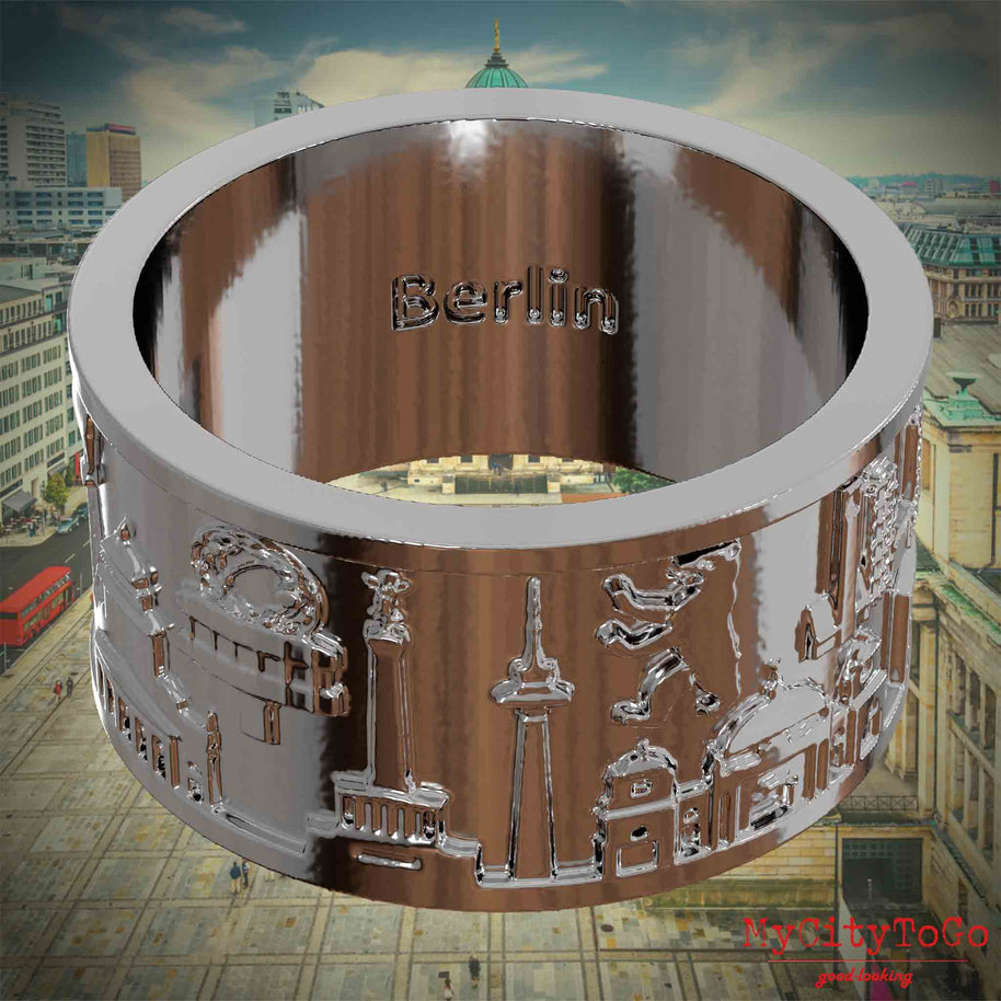 Versilberter Ring mit Reliefs bekannter Sehenswürdigkeiten der Stadt Berlin und einer Gravur des Stadtnamens auf der Innenseite.Den Hintergrund bildet eine Ansicht der Stadt Berlin.