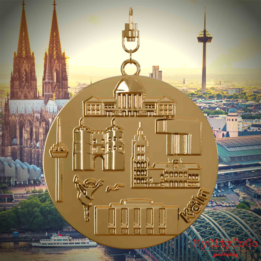 Halskette mit Drehwirbel und Rückseite eines vergoldeten Schmuckanhängers, auf dem Reliefs bekannter Sehenswürdigkeiten der Stadt Koeln abgebildet sind. Den Hintergrund bildet eine Ansicht der Stadt Koeln.