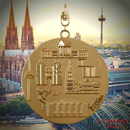 Halskette mit Drehwirbel und Rückseite eines vergoldeten Schmuckanhängers, auf dem Reliefs bekannter Sehenswürdigkeiten der Stadt Koeln abgebildet sind. Den Hintergrund bildet eine Ansicht der Stadt Koeln.