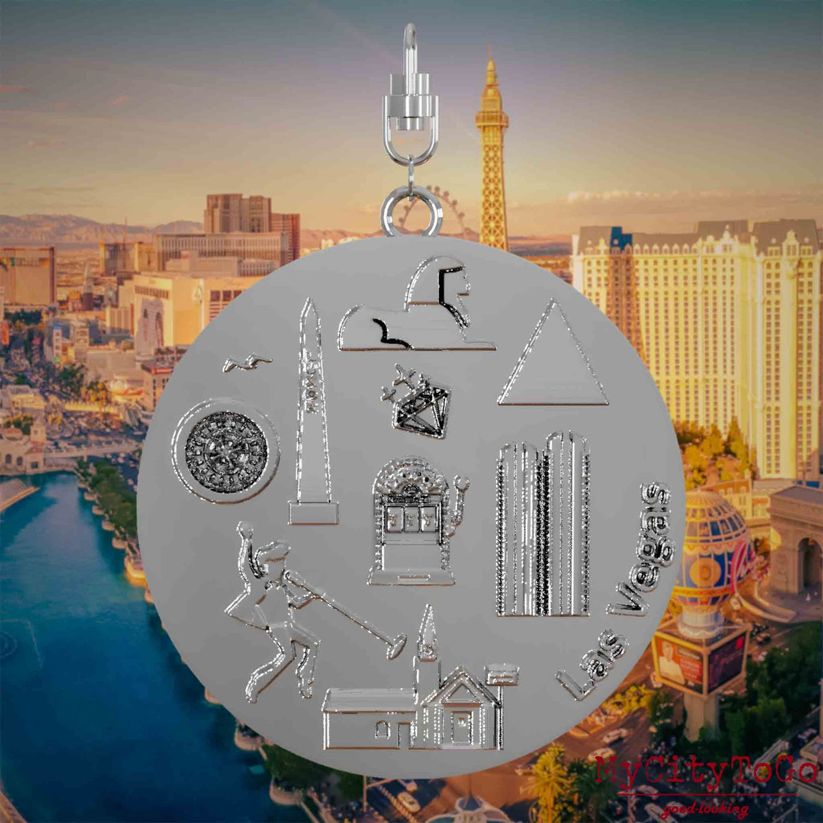 Necklace with swivel clasp and the front of a silver jewelry pendant featuring reliefs of famous Las Vegas landmarks. The background shows a view of the city of Las Vegas.
