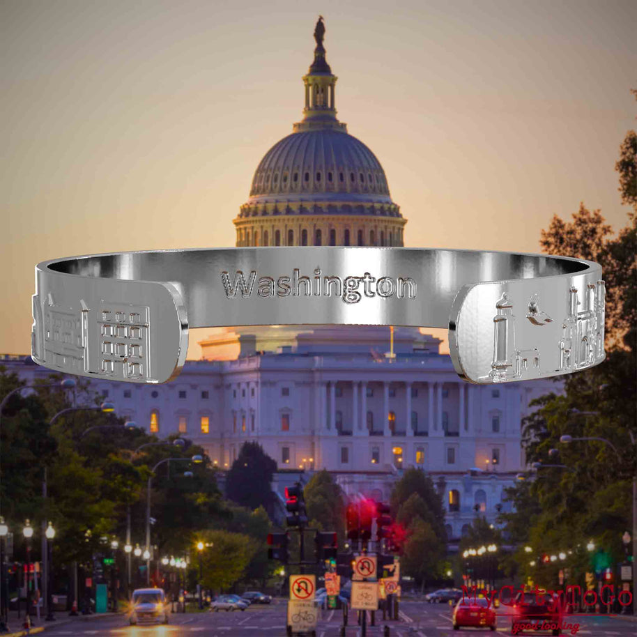 Innenseite eines silbernen Armreifs mit Reliefs bekannter Sehenswürdigkeiten der Stadt Washington und einer Gravur des Stadtnamens. Den Hintergrund bildet eine Ansicht der Stadt Washington.