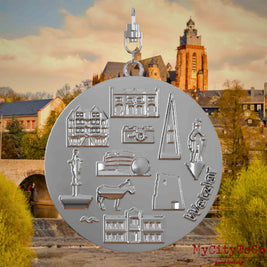 Halskette mit Drehwirbel und Vorderseite eines silbernen Schmuckanhängers, auf dem Reliefs bekannter Sehenswürdigkeiten der Stadt Wetzlar abgebildet sind. Den Hintergrund bildet eine Ansicht der Stadt Wetzlar.
