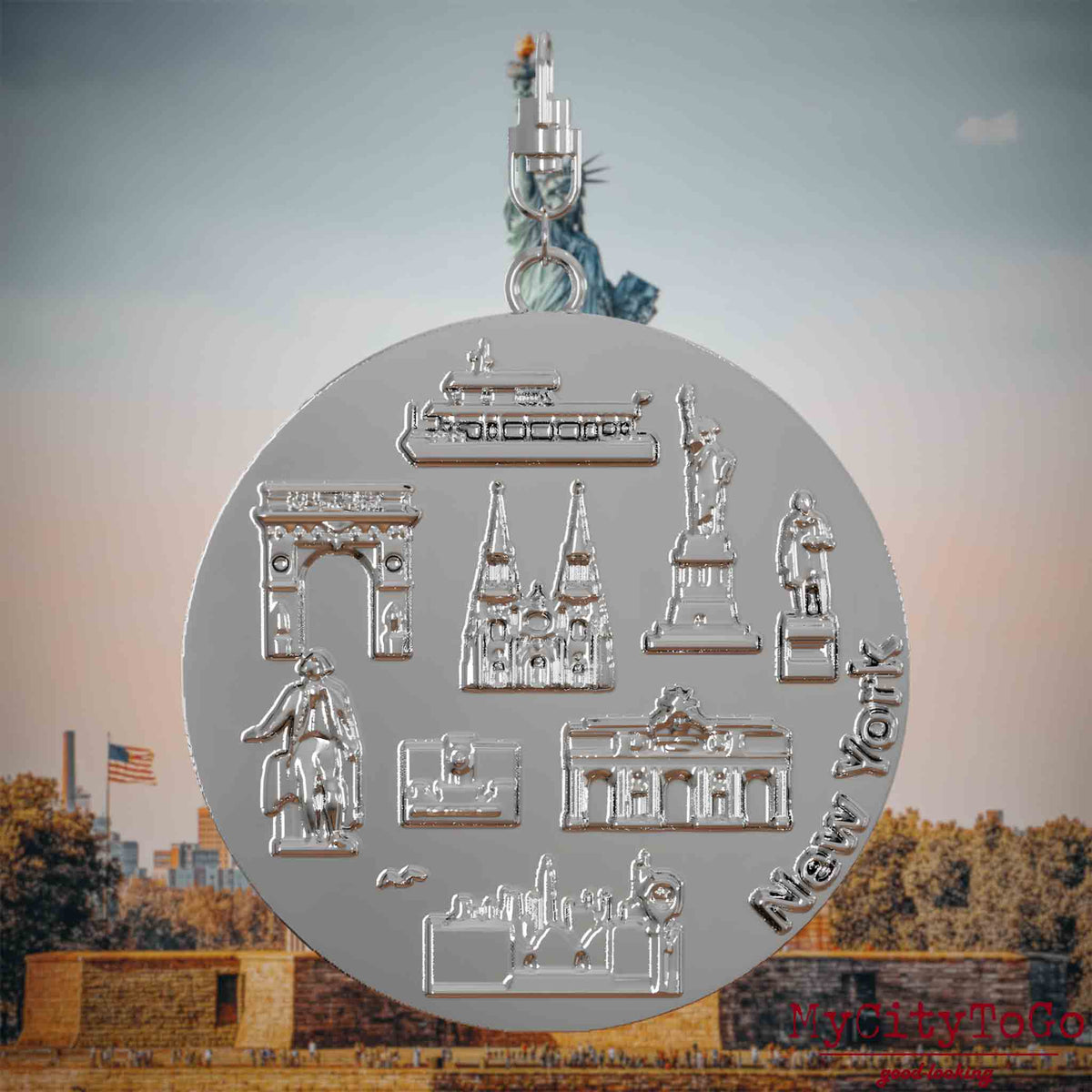 Halskette mit Drehwirbel und Vorderseite eines silbernen Schmuckanhängers, auf dem Reliefs bekannter Sehenswürdigkeiten der Stadt New York abgebildet sind. Den Hintergrund bildet eine Ansicht der Stadt New York.
