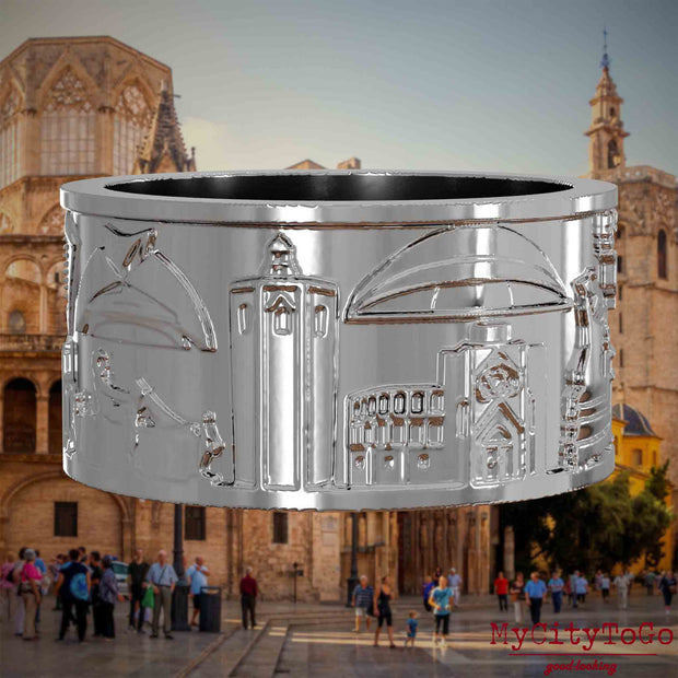 Silberner Ring mit Reliefs bekannter Sehenswürdigkeiten der Stadt Valencia. Den Hintergrund bildet eine Ansicht der Stadt Valencia.