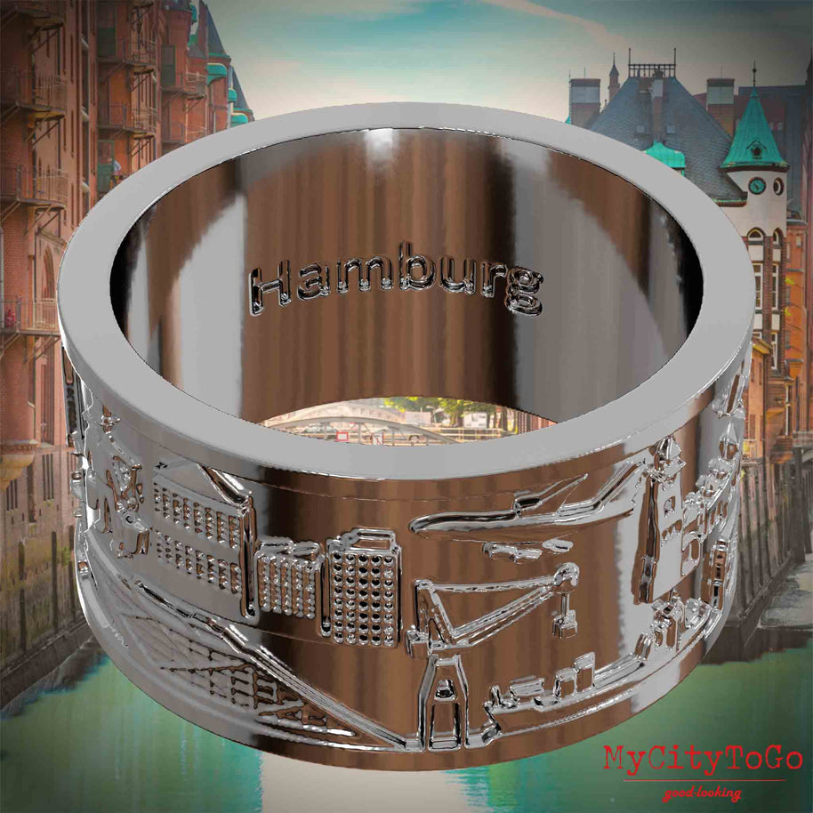 Versilberter Ring mit Reliefs bekannter Sehenswürdigkeiten der Stadt Hamburg und einer Gravur des Stadtnamens auf der Innenseite. Den Hintergrund bildet eine Ansicht der Stadt Hamburg.